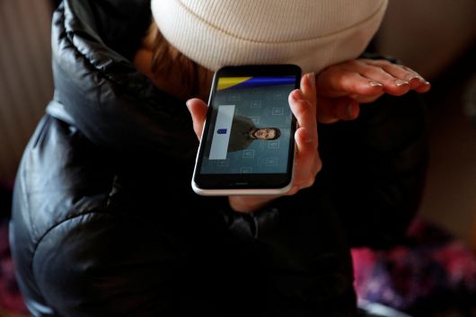 28일 헝가리로 피신한 한 우크라이나 여성이 난민캠프에서 스마트폰으로 젤렌스키 우크라이나 대통령의 연설을 들으며 눈물을 닦고 있다./로이터 뉴스1