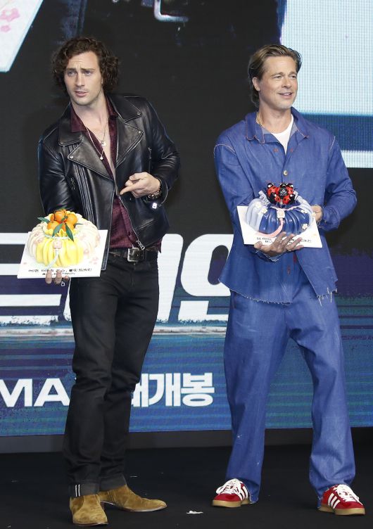 할리우드 배우 애런 테일러 존슨과 브래드 피트가 내한 기자회견에서 복주머니 케이크를 받고 기뻐하고 있다. /뉴스1
