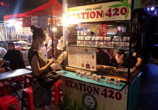 태국 방콕의 유명 관광지인 카오산 로드(Khao San Road)에서 한 여성이 말린 대마를 병에 담아 파는 노점상 앞에 서서 대마를 구경하고 있다. 이곳에서는 대마 1g을 500바트(약 1만9000원)에 팔고 있다. 5g을 사면 1g을 덤으로 준다고 홍보도 하고 있다./게티이미지 코리아