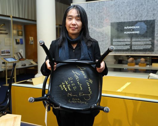 6일(현지 시각) 스웨덴 스톡홀름 노벨 박물관에서 올해 노벨 문학상 수상자인 한강 작가가 수상자만을 위한 특별한 방명록인 박물관 레스토랑 의자에 서명을 남긴 뒤 의자를 들어 보이고 있다. 이전 노벨문학상 수상자인 아니 에르노(2022·프랑스), 욘 포세(2023·노르웨이)의 서명이 보인다. /연합뉴스