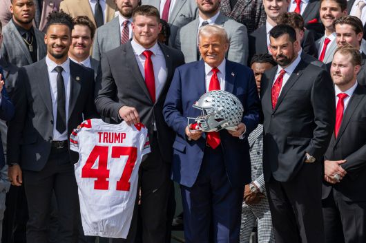 도널드 트럼프 미 대통령이 14일 백악관에서 대학 미식축구 전국 챔피언십 우승팀인 오하이오 주립대팀으로부터 유니폼과 헬멧을 선물로 받고 있다. /EPA 연합뉴스