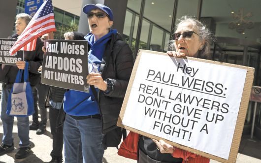 "진짜 변호사는 싸워보지도 않고 포기 안 한다" - 지난 2일 미국 뉴욕의 로펌 '폴 와이스(Paul Weiss)' 앞에서 반(反)트럼프 시위대가 "진짜 변호사들은 싸우지도 않고 포기하지 않는다" "변호사가 아닌 애완견"같은 팻말을 들고 시위를 하고 있다. 트럼프가 과거 자신에게 호의적이지 않았던 이 로펌 소속 변호사들의 연방 정부 보안 인가를 박탈하자, 로펌은 트럼프 행정부에 무료 법률 서비스를 제공하기로 하면서 굴복했다. /EPA 연합뉴스