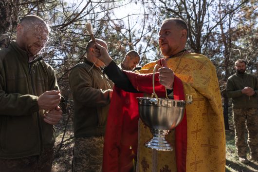 지난 20일 부활절을 맞은 우크라이나 드니프로 지역, 군 목사가 군인들에게 성수(聖水)를 뿌리고 있다. /로이터 연합뉴스