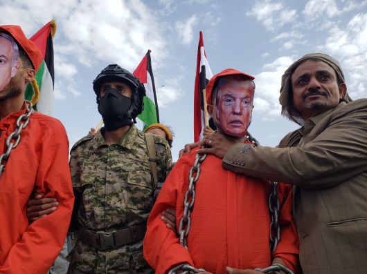 후티 반군 지지자들이 9일 수도 사나에서 트럼프 미국 대통령과 네타냐후 이스라엘 총리의 얼굴 사진을 씌운 사람 목덜미에 체인을 감고, 트럼프의 목을 조르는 시위를 하고 있다./EPA 연합뉴스