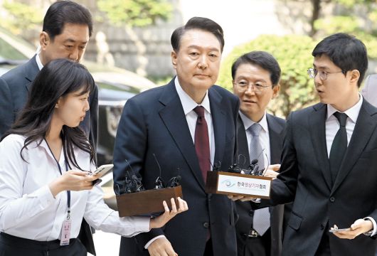 법원 포토라인에 선 尹 '묵묵부답' - 윤석열 전 대통령이 12일 오전 서울 서초구 서울중앙지법에서 열린 내란 사건 3차 공판에 출석하고 있다. 차량에서 내린 윤 전 대통령은 취재진의 질문에 아무 말도 하지 않고 법정으로 향했다. 윤 전 대통령이 법원에 출석하는 모습이 공개된 건 이번이 처음이다. 그동안은 법원 지하 주차장을 통해 비공개로 출석했다. /사진공동취재단