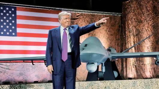 15일 카타르 도하 알우데이드 공군기지를 방문한 도널드 트럼프 대통령이 연설을 들으러 온 미군 병사들을 향해 검지손가락을 앞세우는 특유의 동작을 하고 있다. 뒤로는 미군이 운용하는 군사용 드론과 대형 성조기가 보인다. /로이터 연합뉴스