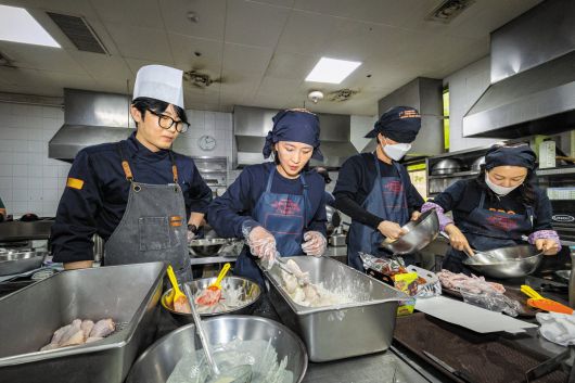 다른 예비 치킨집 사장들과 함께 교육 받은 본지 정시행 기자(왼쪽에서 두 번째)가 반죽옷 입힌 닭을 튀김 가루 트레이에 옮겨담고 있다. 튀기는 시간 10분을 포함, 주문 받은 지 15분 만에 배달로 넘겨야 한다. 위생 마스크는 사진 촬영 때만 잠시 벗었다. /이건송 영상미디어 기자