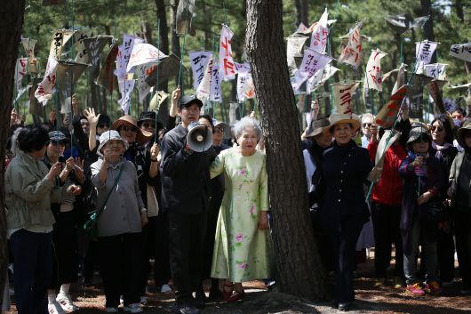 25일 강릉 순포해변 영화 '청명과 곡우 사이' 촬영 현장의 유준상 감독(가운데 확성기 든 사람)과 주연 배우 박정자(유 감독 오른쪽 꽃무늬 원피스). '조문객' 150여명이 든 만장엔 배우 박정자의 출연작 제목이 적혀 있다./강릉=이태훈 기자