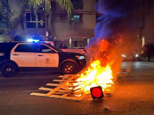 9일 밤 미국 로스엔젤레스 시가지에서 불타오르는 나무 더미를 경찰 진압 차량이 돌파하고 있다./오로라 특파원
