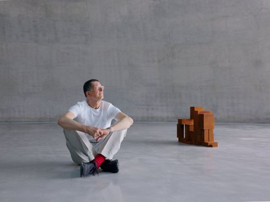 자신의 첫 상설 전시관 ‘Ground’에 앉은 조각가 앤터니 곰리. 그는 “공간과 작품이 함께 성장하는 경험을 처음 하게 됐다”고 했다. 옆엔 무릎을 모으고 뒤로 기댄 사람 모습을 표현한 그의 조각./뮤지엄 산