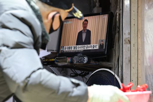 A vendor at a traditional market in Seoul watches a news report on Jan. 15, 2025, as a joint investigative unit of the Corruption Investigation Office for High-ranking Officials and police carries out a second arrest warrant for former President Yoon Suk-yeol./News1