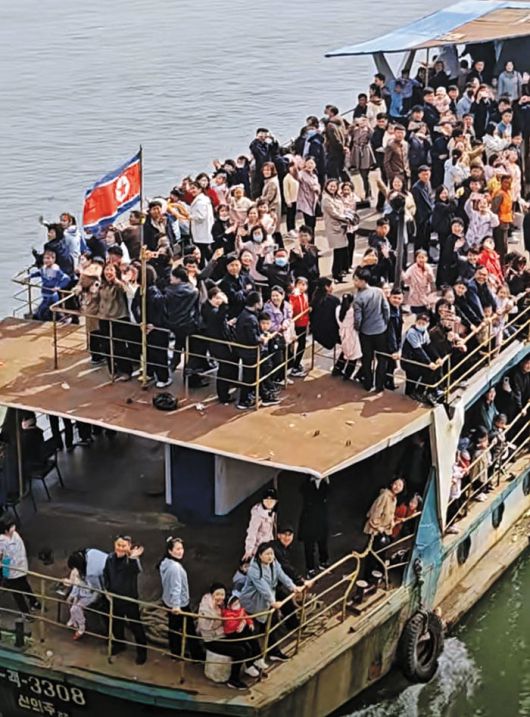 North Korean residents wave toward Dandong, China, from a cruise ship crossing the Yalu River from Sinuiju in April 2025./Douyin