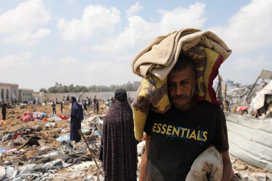 21일 이스라엘의 공습을 받은 가자지구 중부 데이르알발라의 한 난민캠프에서 한 남성이 허탈한 표정으로 소지품을 챙겨 떠나고 있다./AFP 연합뉴스