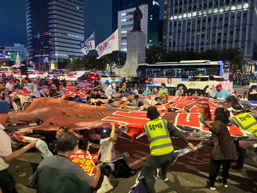 13일 오후 서울 종로구 광화문광장에서 촛불행동 시위대가 도널드 트럼프 미국 대통령 얼굴이 그려진 대형 플래카드를 찢는 퍼포먼스를 벌이고 있다. /고유찬 기자