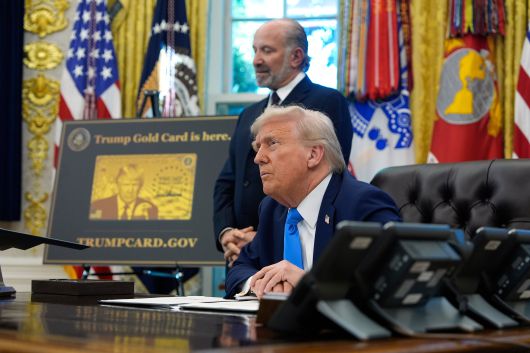 트럼프 대통령이 19일 워싱턴 백악관 오벌 오피스에서 하워드 러트닉 상무장관 함께 기자들의 질문을 듣고 있다. 옆에 골드카드 시안이 놓여져 있다. /AP 연합뉴스