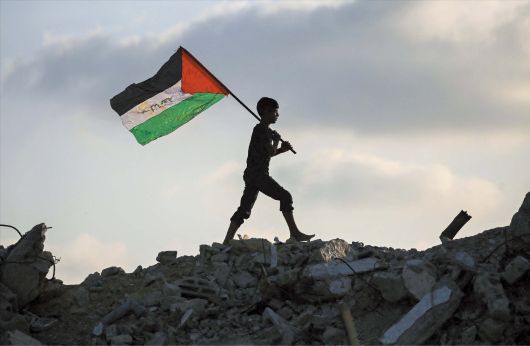 AFP 연합뉴스 22일 팔레스타인 가자지구 중부 부레이지 난민 캠프에서 팔레스타인 국기를 둘러멘 어린이가 파괴된 건물 잔해 위를 걷고 있다. 2023년 10월 시작된 이스라엘과 가자지구 무장 단체 하마스의 전쟁이 장기화하고 민간인 희생이 늘면서, 전날 영국·호주·캐나다·포르투갈에 이어 이날 프랑스도 팔레스타인을 국가로 공식 인정하고 이스라엘에 대한 외교적 압박에 나섰다.