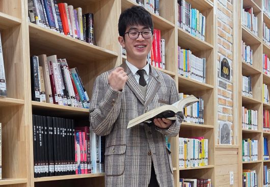 올해 수능에서 수능 전 과목 만점을 받은 이하진군이 도서관에서 칼 세이건의 책 '코스모스'를 들고 포즈를 취하고 있는 모습. 이군은 공부 비결로 스마트폰 대신 책에 빠져 살았던 것이 도움이 됐다고 꼽았다. /표태준 기자