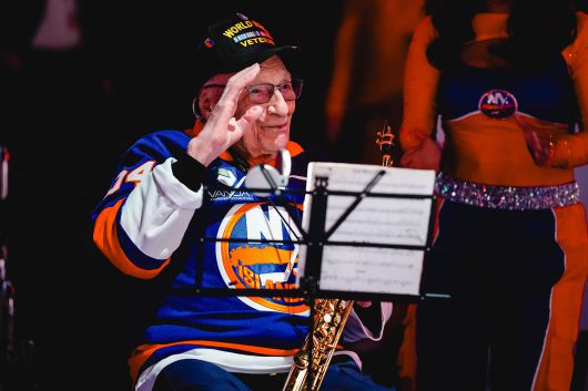 제2차 세계대전 참전 용사인 도미닉 크리텔리가 27일 NHL(북미아이스하키리그) 뉴욕 아일랜더스와 뉴욕 레인저스 경기에 앞서 색소폰으로 미국 국가(國歌)를 연주한 뒤 경례 포즈를 취하고 있다. /뉴욕 아일랜더스 X