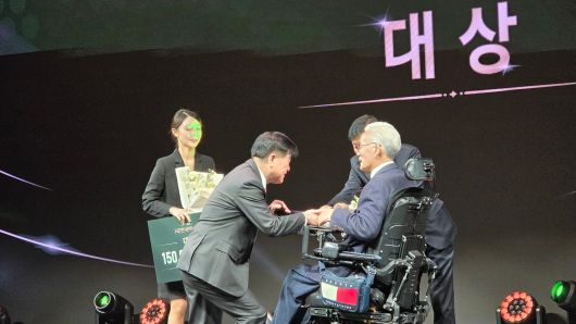 지난달 'HD현대 1% 나눔재단'의 아너상 시상식에서 장애가 있는 수상자에게 무릎을 꿇고 상패를 전달하고 있는 권오갑 명예회장(왼쪽). /HD현대 제공