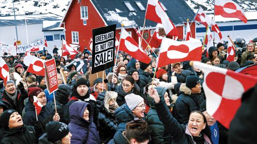 지난 17일 덴마크 자치령 그린란드 주민들이 그린란드 국기와 ‘그린란드는 판매용이 아니다’라는 구호가 적힌 팻말을 들고 수도 누크에 있는 미국 영사관 앞에 모여 항의 집회를 열고 있다. 최근 도널드 트럼프 미국 행정부가 그린란드를 미국으로 편입하겠다는 의지를 거듭 드러내자 이에 반발한 그린란드 주민들의 집회가 잇따르고 있다. /게티이미지코리아
