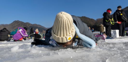 21일 강원도 화천산천어축제장에서 한 어린이가 얼음 구멍 아래를 내려다 보고 있다./김지호 기자