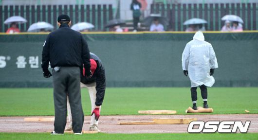 [OSEN=인천, 최규한 기자] 19일 오후 인천 SSG랜더스필드에서 ‘2025 신한 SOL Bank KBO리그’ SSG 랜더스와 LG 트윈스의 경기가 열렸다.이날 홈팀 SSG은 송영진, 방문팀 LG는 손주영을 선발로 내세웠다.4회초 1사 1, 2루 상황 LG 문성주 타석을 앞두고 우천으로 경기가 중단됐다. 젖은 내야를 정비하는 SSG 그라운드 관리 요원들. 2025.04.19 / dreamer@osen.co.kr