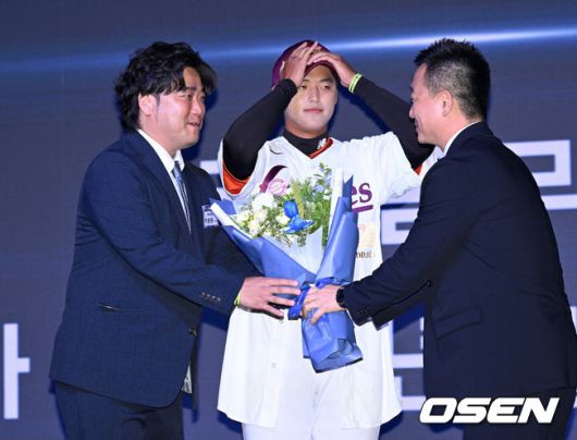 [OSEN=이대선 기자] 17일 오후 7일 오후 서울 롯데호텔 월드에서 ‘2026 KBO 신인 드래프트’가 열렸다.이번 드래프트는 전면 드래프트 방식으로 총 11라운드에 걸쳐 진행된다. 대상자는 총 1천261명으로, 고등학교 졸업 예정자 930명, 대학교 졸업 예정자 216명, 얼리 드래프트 신청자 51명, 해외 아마추어·프로 출신 선수 19명이다. 이 중 최대 110명이 KBO 10개 구단의 부름을 받게 된다.키움에 지명된 북일고 박준현의 아버지 박석민 전 코치가 꽃다발을 받고 있다. 2025.09.17 /sunday@osen.co.kr