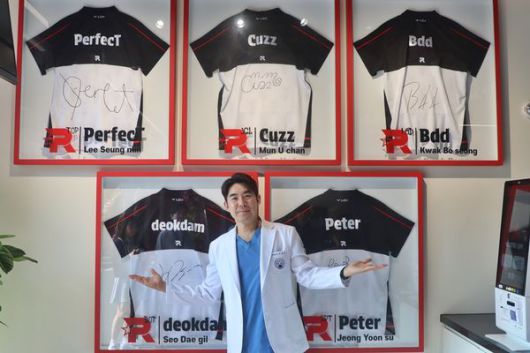 자생한방병원 이진호 병원장이 KT롤스터 카페 벽에 전시된 선수단 친필 사인 유니폼 앞에서 기념사진을 촬영하고 있다.