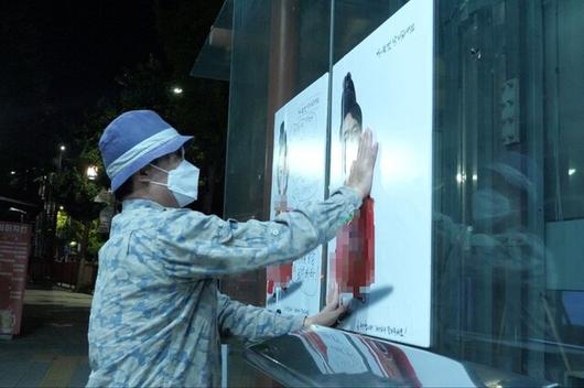 팝아티스트 이하 작가가 13일 오전 윤석열 대통령 풍자 포스터를 붙이고 있다. 이씨 페이스북 갈무리.