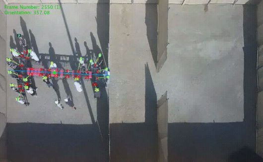 26명의 사람이 T자 모양 물체를 함께 옮기고 있다.