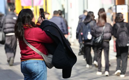 서울의 낮 기온이 최고 10도까지 올라가는 등 포근한 날씨를 보이는 지난 14일 서울 중구 명동에서 겉옷을 손에 든 관광객이 기념촬영을 하고 있다. 연합뉴스