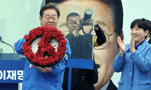 이재명 더불어민주당 대통령 후보가 20일 오후 경기도 고양시 일산문화공원에서 유세 시작에 앞서 장미로 만든 기표 용구 모양의 꽃다발을 선물받고 있다. 공동취재사진