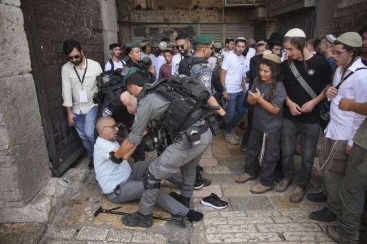 26일(현지시각) 예루살렘 구시가지에서 이스라엘 경찰들이 쓰러진 팔레스타인 남성을 일으켜 세우고 있다. 예루살렘/AP 연합뉴스