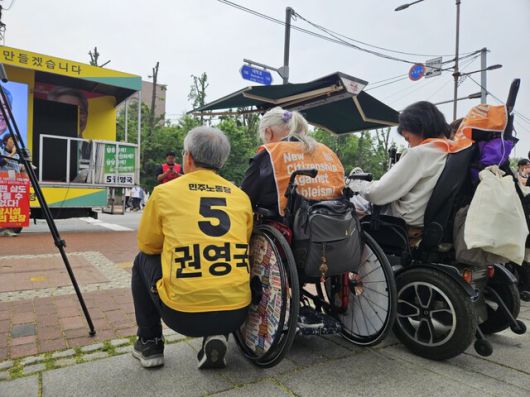 권영국 민주노동당 대통령 후보가 2일 오전 서울 종로구 마로니에공원 앞에서 박경석 전국장애인차별철폐연대 대표 옆에 앉아 다른 활동가의 발언을 듣고 있다. 류석우 기자