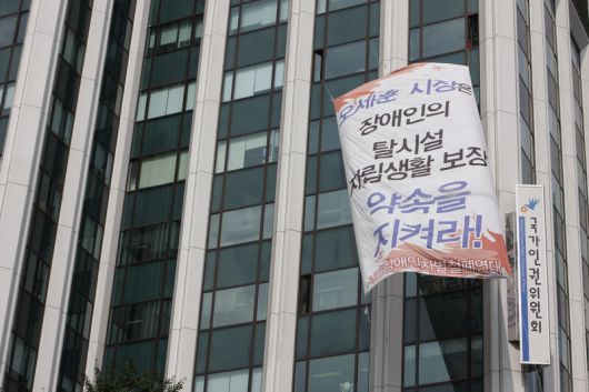 탈시설 자립주택 등을 요구하며 장애인 생활시설에서 나와 서울 대학로 노숙 농성과 국가인권위원회 점거 농성을 벌였던 중증 장애인들이 2009년 8월4일 서울시가 이들의 요구를 일부 수용하는 계획을 발표하자 농성을 중단하고 인권위 건물 외벽에 걸었던 대형 펼침막을 내리고 있다. 김정효 기자 hyopd@hani.co.kr