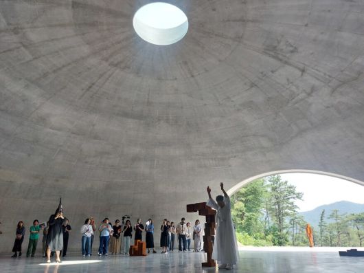 19일 오전 원주 뮤지엄 산 경내에서 공개된 앤터니 곰리와 안도 다다오의 협업 작품공간 ‘그라운드’의 공연 현장. 원로 춤꾼 홍신자씨(가운데 흰옷 입은 사람)와 생황 연주자 김효영씨(왼쪽 악기 부는 사람)가 앤터니 곰리의 조형물을 사이에 두고 퍼포먼스를 벌이고 있다. 오른쪽 트인 출구로는 원주의 드넓은 산야가 눈에 들어온다. 노형석 기자
