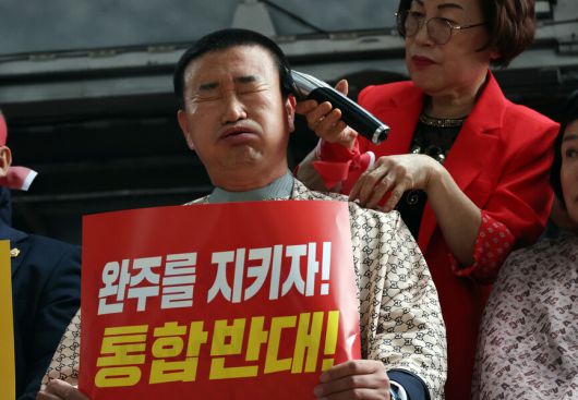 김관영 전북자치도지사의 완주군 방문이 예정된 25일 완주군청사 앞에 설치한 무대에서 유의식 완주군의회 의장을 비롯한 의원 10명이 전주·완주 통합을 반대하며 삭발하고 있다. 연합뉴스