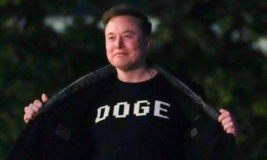 일론 머스크가 지난 3월9일(현지시각) 미국 워싱턴 백악관에 도착한 뒤 마린 원에서 내려 백악관 남쪽 뜰을 걸으며 ‘정부효율부(DOGE)’라고 적힌 티셔츠를 선보이고 있다. 워싱턴/AFP 연합뉴스