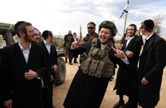 올해 1월5일(현지시각) 이스라엘 남부 도시 스데로의 한 언덕에서 군모와 탄약을 운반하는 군인으로부터 조끼와 헬멧 등을 빌려입은 이스라엘 초정통 유대인 남성이 동료들과 함께 웃고 있다. 스데로/AFP 연합뉴스