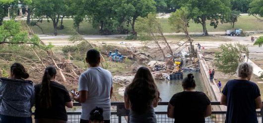 6일(현지시각) 미국 텍사스주 커빌에서 행인들이 최근 홍수로 인한 과달루페 강변의 피해를 내려다보고 있다. AP 연합뉴스