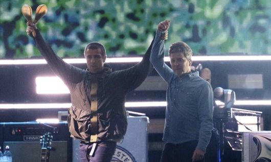 지난 4일(현지시각) 영국 웨일스 카디프 프린시팰리티 스타디움에서 16년 만에 컴백 무대를 펼친 록 밴드 오아시스의 리암 갤러거(왼쪽)가 형 노엘 갤러거의 손을 잡고 번쩍 들어올리고 있다. 카디프/AP 연합뉴스