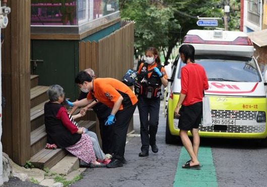 9일 서울역 앞 쪽방촌 골목에 앉아 대화하던 주민이 쓰러지자 119 구급대원들이 출동하고 있다. 연합뉸스