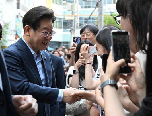 이재명 대통령이 11일 저녁 외식 행사가 열린 서울 종로구의 한 식당으로 걸어서 이동하던 도중 시민들과 인사하고 있다. 대통령실사진기자단