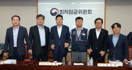 10일 정부세종청사에서 열린 제12차 전원회의에서 내년 최저임금을 시간당 1만320원으로 17년만에 합의로 결정한 공익위원-사용자위원-근로자위원들이 손을 잡고 기념촬영을 하고 있다. 연합뉴스