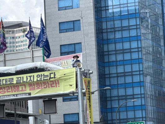 22일 세종호텔 앞 도로 한복판에 놓인 10ｍ 높이의 철제 구조물 위에서 농성을 벌이고 있는 세종호텔 해고 노동자 고진수씨가 원로들의 응원해 화답하고 있다. 정봉비 기자