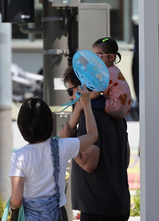 전국 대부분 지역에 폭염경보가 발효된 27일 오후 서울 종로구 광화문광장에서 한 시민이 남편과 딸에게 부채질을 해주고 있다. 김혜윤 기자 unique@hani.co.kr