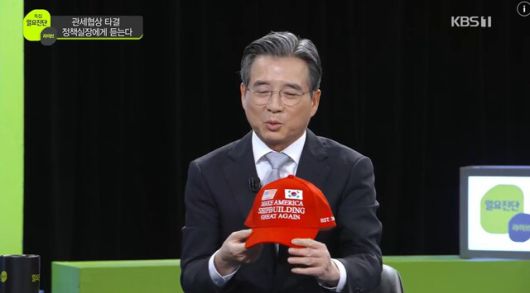 김용범 대통령실 정책실장이 한국방송(KBS) ‘일요진단 라이브’에 출연해 한미 관세협상의 막전막후를 설명하고 있다. 김 실장이 정부가 도널드 트럼프 미국 대통령을 설득하려 제작한 ‘마스가’(MASGA: Make American Shipbuilding Great Again) 모자를 손에 들고 있다. 한국방송 갈무리