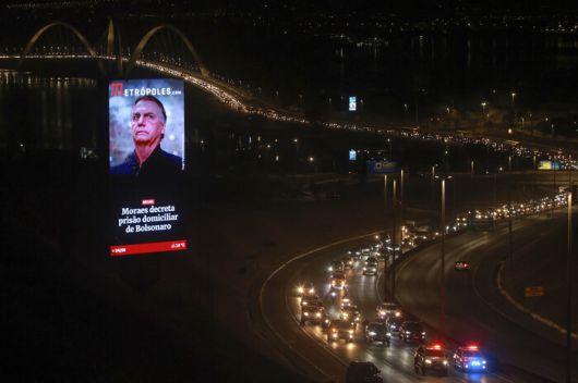 브라질 대법원이 내린 자이르 보우소나루 전 대통령의 가택연금 명령을 알리는 대형 전광판. 4일(현지시각) 보우소나루 전 대통령의 지지자들이 차량 시위를 벌이며 지나가고 있다. 보우소나루 전 대통령은 2022년 대선 패배 이후에도 권력을 유지하려 쿠데타를 주도한 혐의로 재판을 받고 있다. AP연합뉴스