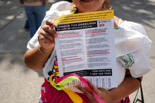 6일(현지시각) 미국 일리노이주 시카고에서 열린 멕시코 독립기념일 퍼레이드 중 참가자가 이민세관단속국과 관련한 안내문을 들고 있다. 로이터 연합뉴스