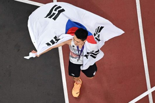 ‘스마일 점퍼’ 우상혁(용인시청)이 16일 일본 도쿄에서 열린 2025 세계육상선수권 높이뛰기 결선에서 은메달을 차지한 뒤 태극기를 들고 트랙을 돌고 있다. 도쿄/AFP 연합뉴스